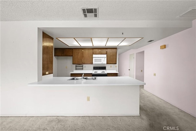 kitchen featuring kitchen peninsula, a textured ceiling, light colored carpet, range with electric cooktop, and sink