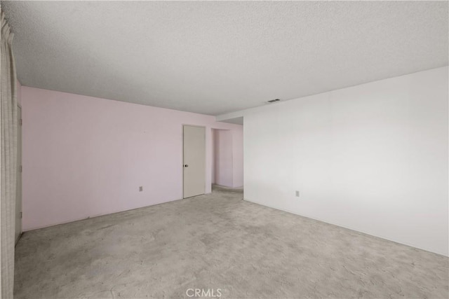 spare room featuring a textured ceiling and light carpet