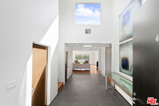 hallway featuring a high ceiling and dark tile patterned floors