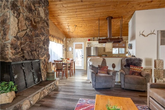 living room featuring vaulted ceiling, wood-type flooring, an inviting chandelier, a stone fireplace, and wooden ceiling