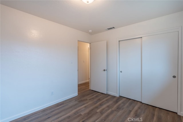 unfurnished bedroom featuring a closet and dark hardwood / wood-style floors