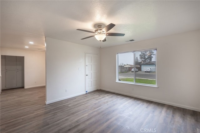 empty room featuring ceiling fan, a textured ceiling, and dark hardwood / wood-style floors