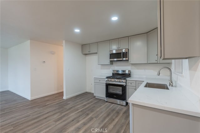 kitchen featuring appliances with stainless steel finishes, sink, gray cabinetry, and light stone counters