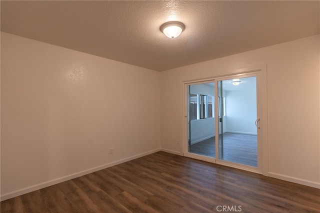 empty room with a textured ceiling and dark wood-type flooring