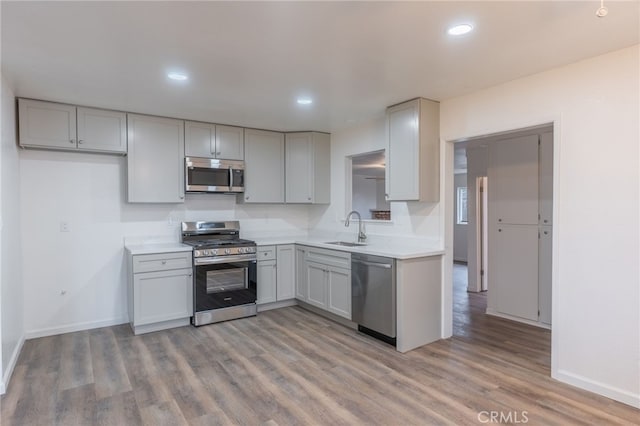 kitchen featuring gray cabinets, sink, appliances with stainless steel finishes, and light hardwood / wood-style flooring