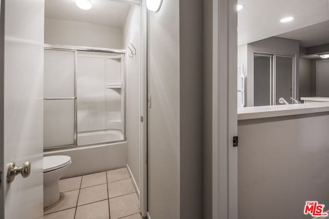 full bathroom with combined bath / shower with glass door, sink, tile patterned flooring, and toilet