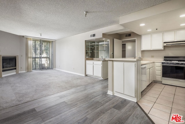 kitchen with white cabinetry, light colored carpet, kitchen peninsula, and white appliances