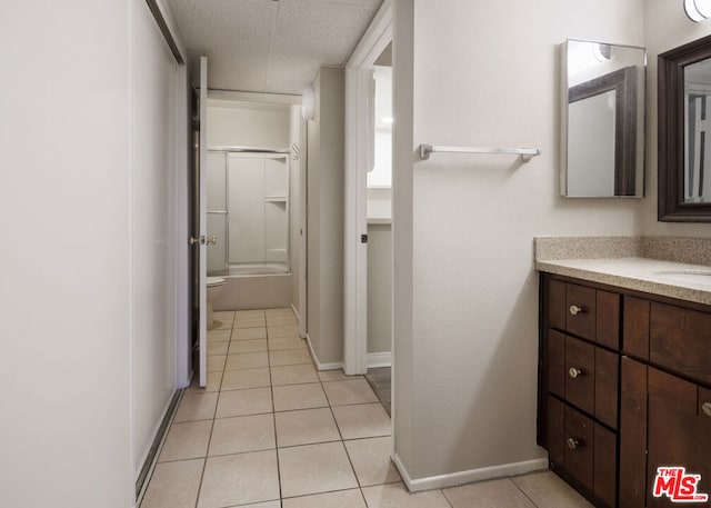 full bathroom featuring toilet, bath / shower combo with glass door, vanity, tile patterned floors, and a textured ceiling