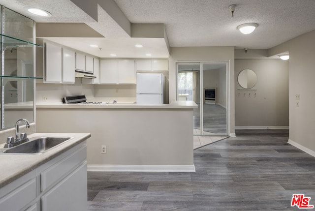 kitchen with white fridge, dark hardwood / wood-style floors, range, white cabinets, and sink