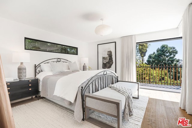 bedroom featuring wood-type flooring and access to outside