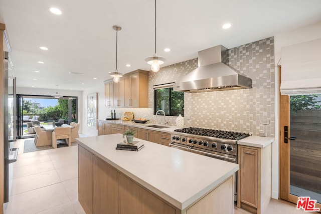 kitchen featuring a wealth of natural light, wall chimney exhaust hood, tasteful backsplash, and sink