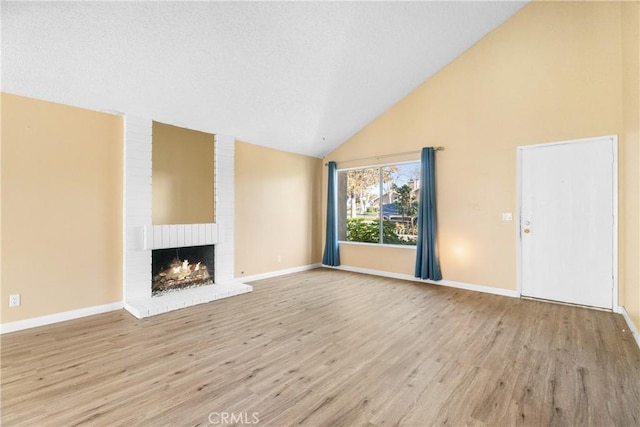 unfurnished living room featuring a fireplace, light hardwood / wood-style floors, and lofted ceiling