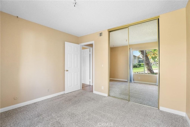 unfurnished bedroom featuring a textured ceiling, a closet, and carpet flooring