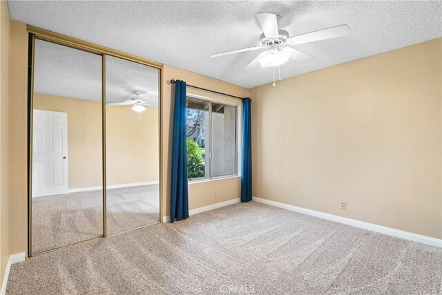 unfurnished bedroom featuring a closet, ceiling fan, a textured ceiling, and carpet floors