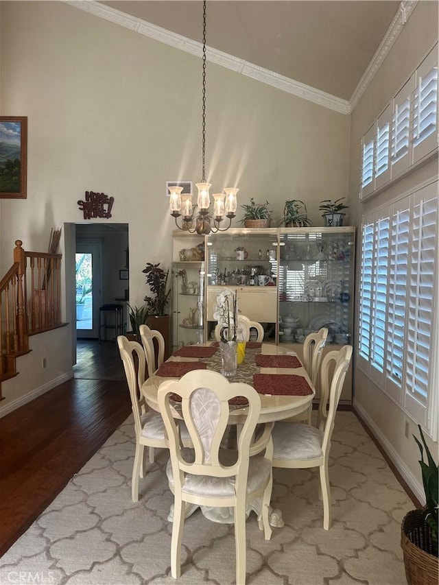 dining area with a wealth of natural light, an inviting chandelier, ornamental molding, and hardwood / wood-style floors