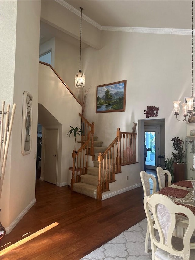 dining area with dark wood-type flooring, crown molding, and a notable chandelier