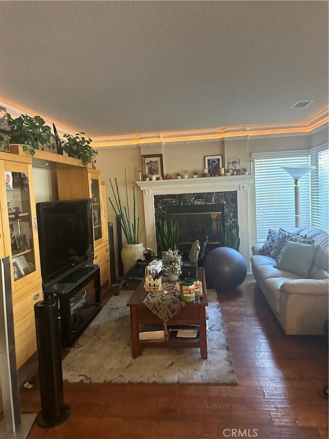 living room featuring hardwood / wood-style flooring, ornamental molding, and a fireplace