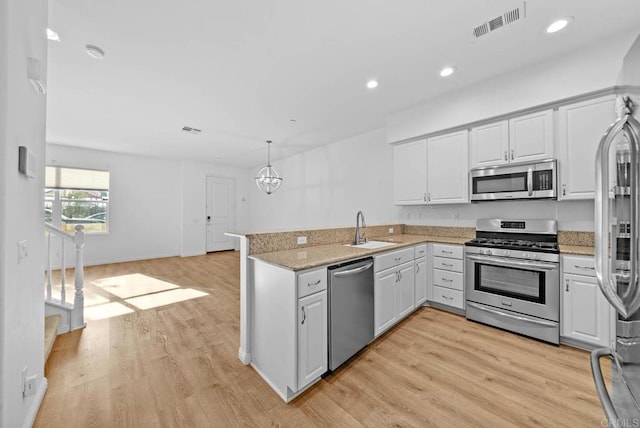 kitchen featuring white cabinetry, kitchen peninsula, stainless steel appliances, and hanging light fixtures