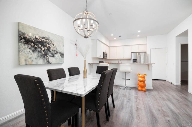 dining space with sink, a notable chandelier, and light wood-type flooring