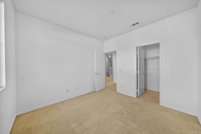 unfurnished bedroom featuring light carpet and a closet