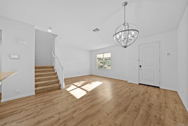 unfurnished living room with an inviting chandelier and light wood-type flooring