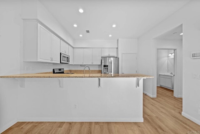 kitchen with kitchen peninsula, a kitchen bar, and appliances with stainless steel finishes