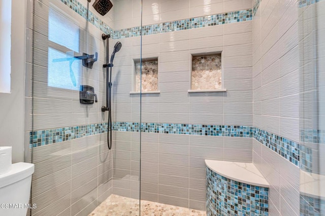 bathroom featuring toilet, tile walls, and tiled shower