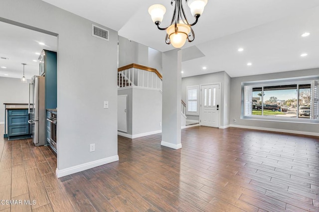 unfurnished living room with dark wood-type flooring and an inviting chandelier