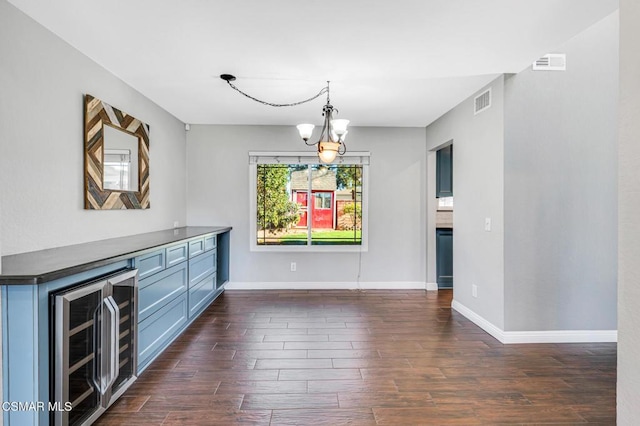 unfurnished dining area featuring a chandelier and wine cooler