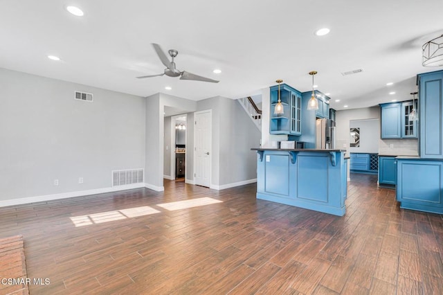 kitchen featuring ceiling fan, pendant lighting, decorative backsplash, a breakfast bar area, and blue cabinets