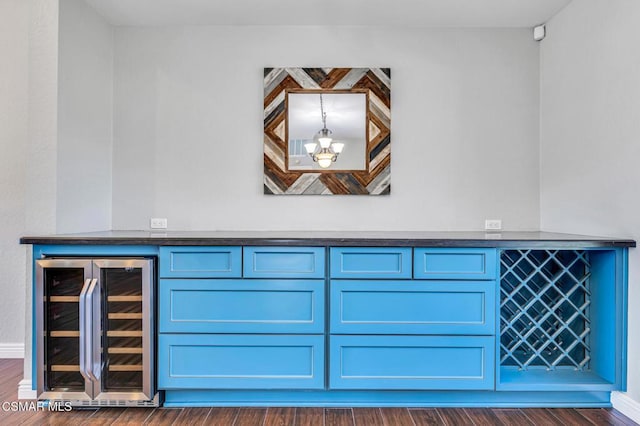 interior details with indoor bar, wine cooler, wood-type flooring, and a chandelier