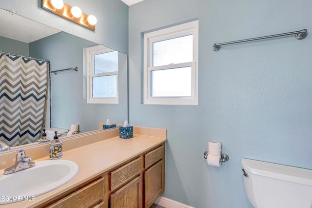 bathroom featuring toilet, vanity, and a shower with shower curtain