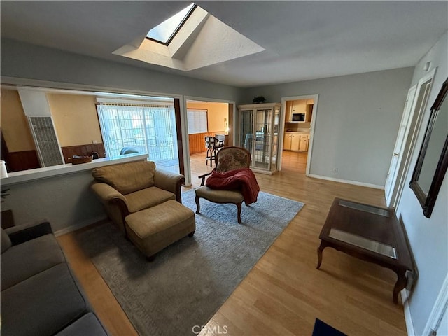 living room with light wood-type flooring and a skylight