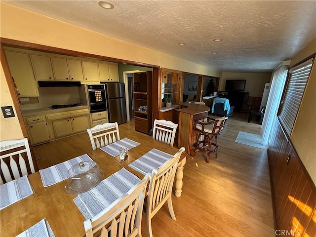 dining space with light hardwood / wood-style floors and a textured ceiling