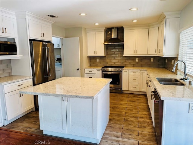 kitchen with appliances with stainless steel finishes, wall chimney range hood, and white cabinetry