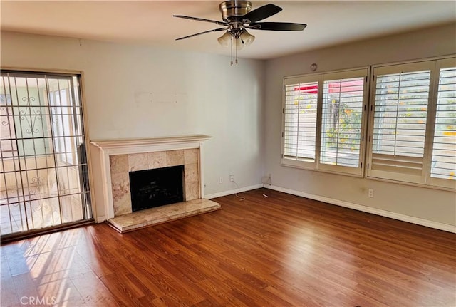 unfurnished living room with ceiling fan, dark wood-type flooring, and a tile fireplace