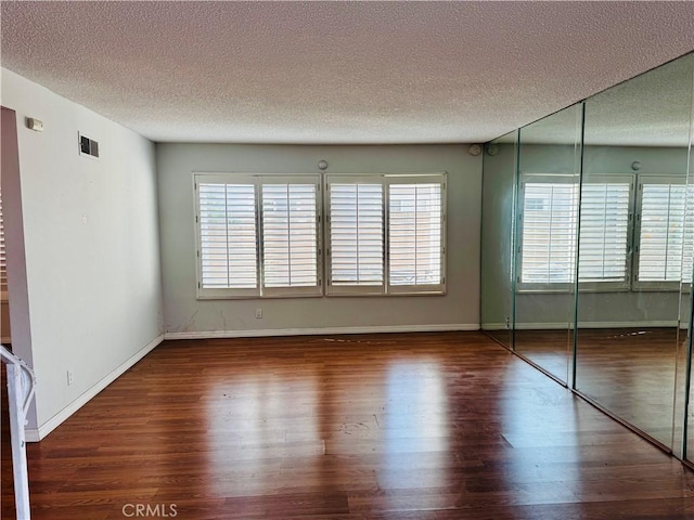 spare room featuring a textured ceiling and dark hardwood / wood-style flooring