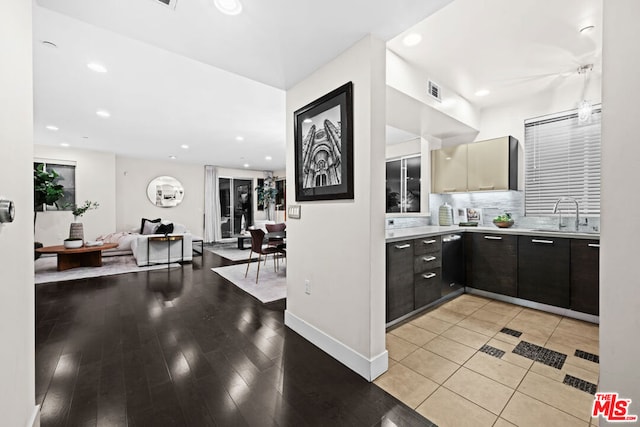 kitchen with light hardwood / wood-style floors, sink, backsplash, and dark brown cabinetry