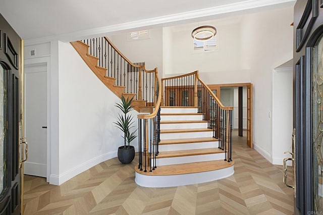 entryway with light parquet flooring and ornamental molding