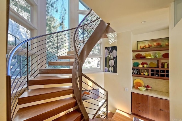 stairway with a wealth of natural light and hardwood / wood-style floors