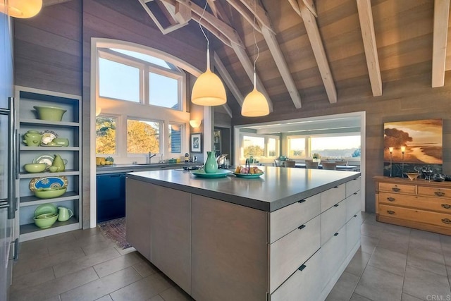 kitchen with wood walls, a kitchen island, white cabinets, and decorative light fixtures