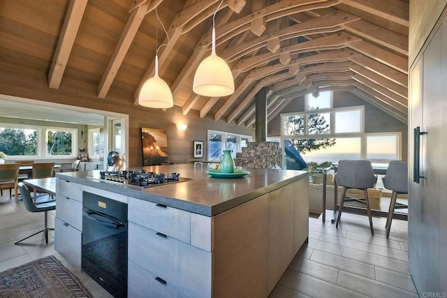 kitchen with vaulted ceiling with beams, a kitchen island, and pendant lighting