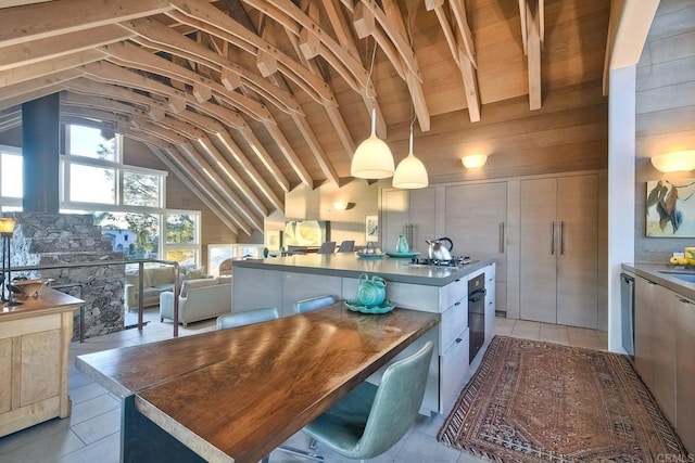 kitchen featuring light tile patterned floors, wood walls, wall oven, vaulted ceiling with beams, and a center island