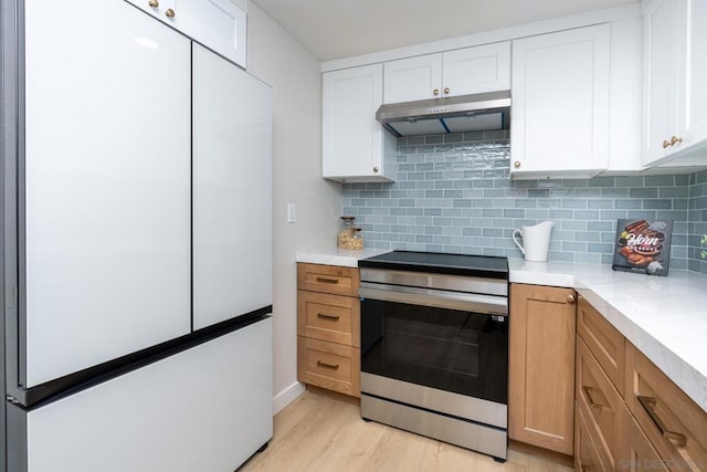 kitchen featuring stainless steel range, white cabinetry, backsplash, and white refrigerator