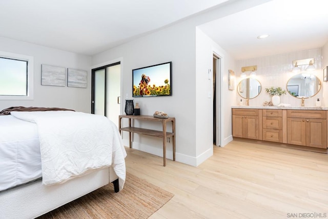 bedroom with ensuite bathroom and light wood-type flooring