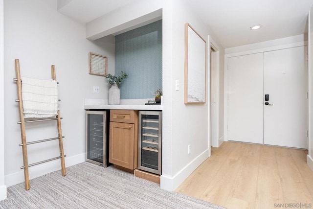 bar featuring beverage cooler and light hardwood / wood-style flooring