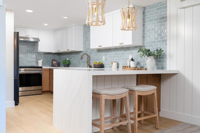 kitchen with tasteful backsplash, light hardwood / wood-style floors, a breakfast bar, appliances with stainless steel finishes, and white cabinets