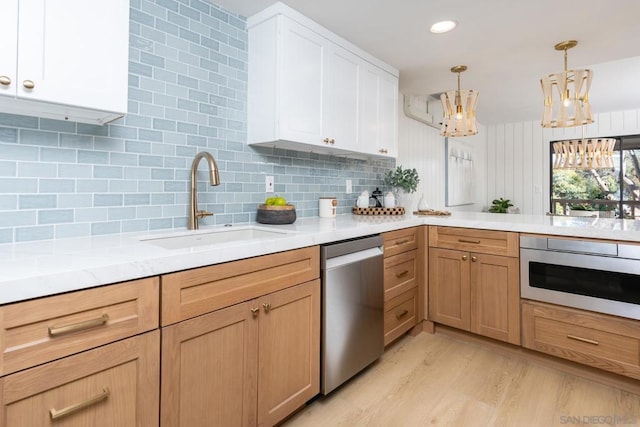 kitchen with decorative light fixtures, white cabinets, dishwasher, and sink