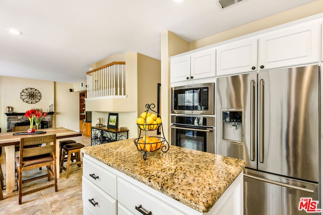 kitchen featuring light stone countertops, white cabinets, appliances with stainless steel finishes, and a kitchen island