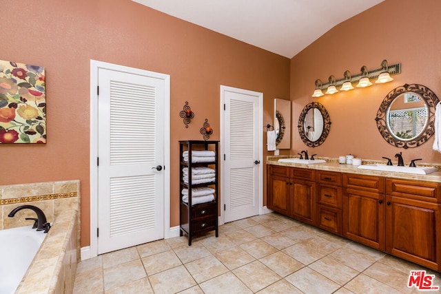 bathroom with lofted ceiling, vanity, tiled bath, and tile patterned floors